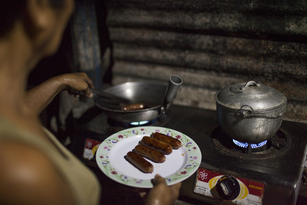A mother cooks sausage for breakfast for her family at home in Barangay Puypuy, Laguna, Philippines