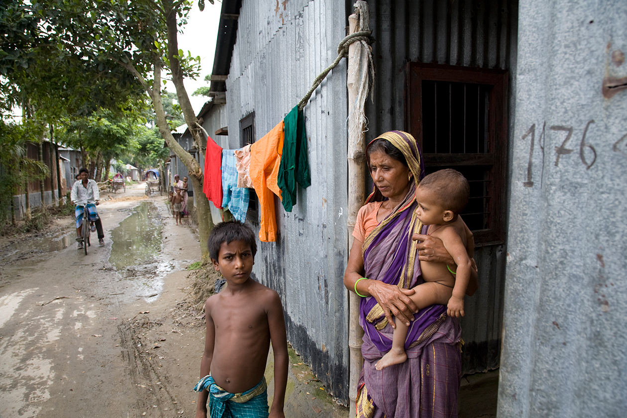 A woman and her children stand outside their door in rural Bangladesh.
