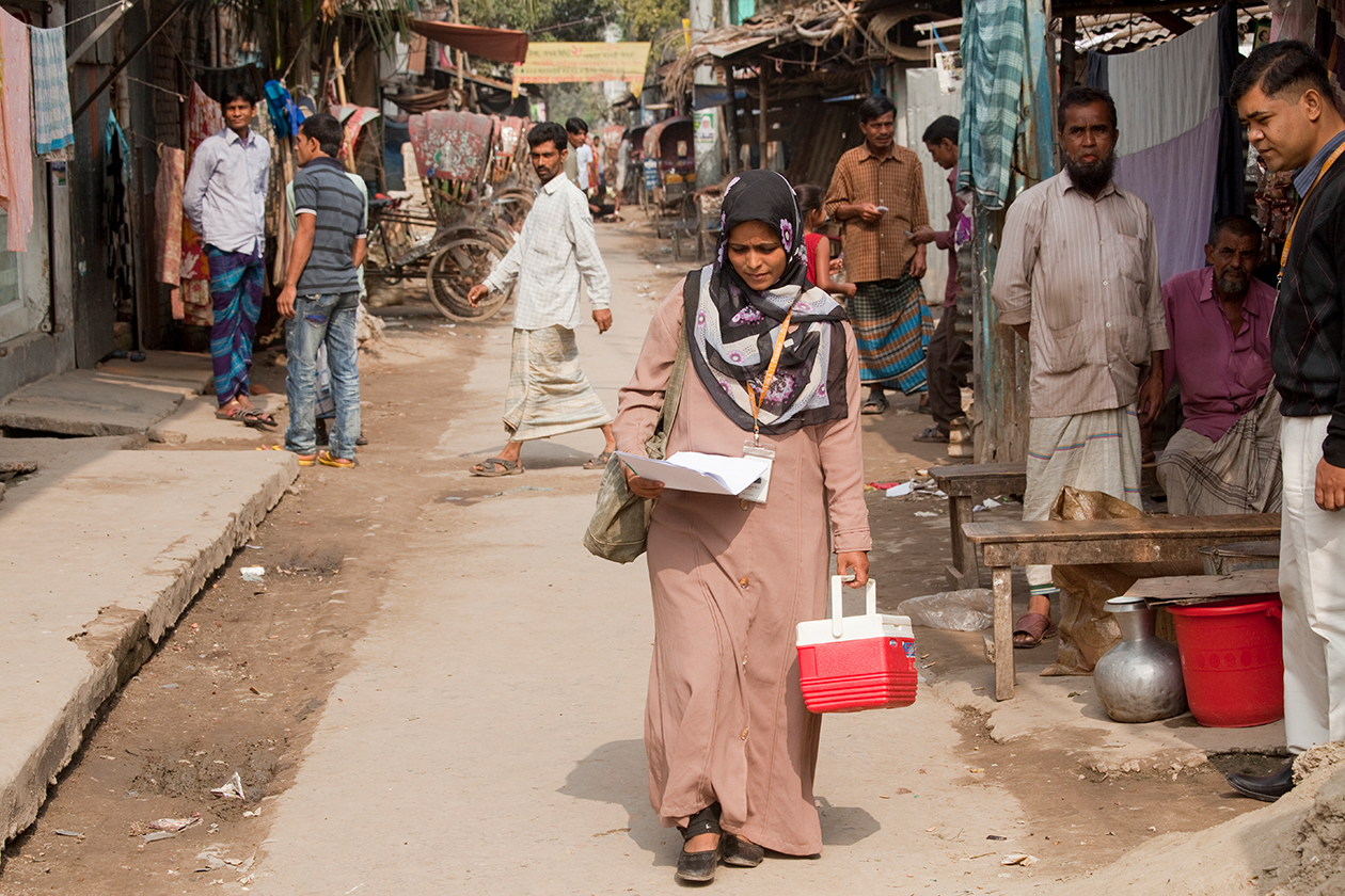 A health worker in Bangladesh walks through a market, on her way to a house call.