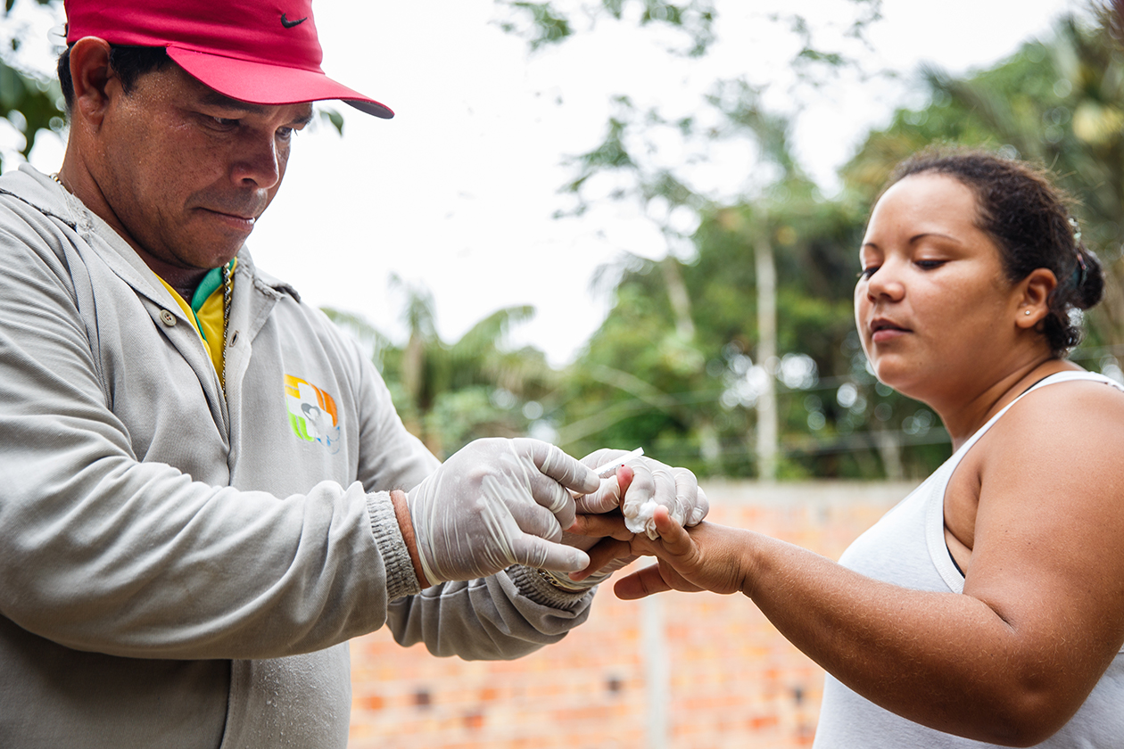 A Brazilian community health worker draws blood from a resident of a rural area.