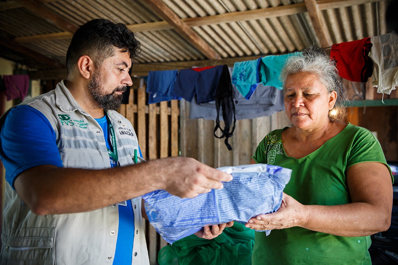 A community health worker delivers a new insecticide-treated bed net to a resident in a rural area of Manaus, Brazil.