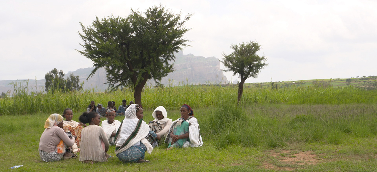 A group of women sit in a field in rural Ethiopia.