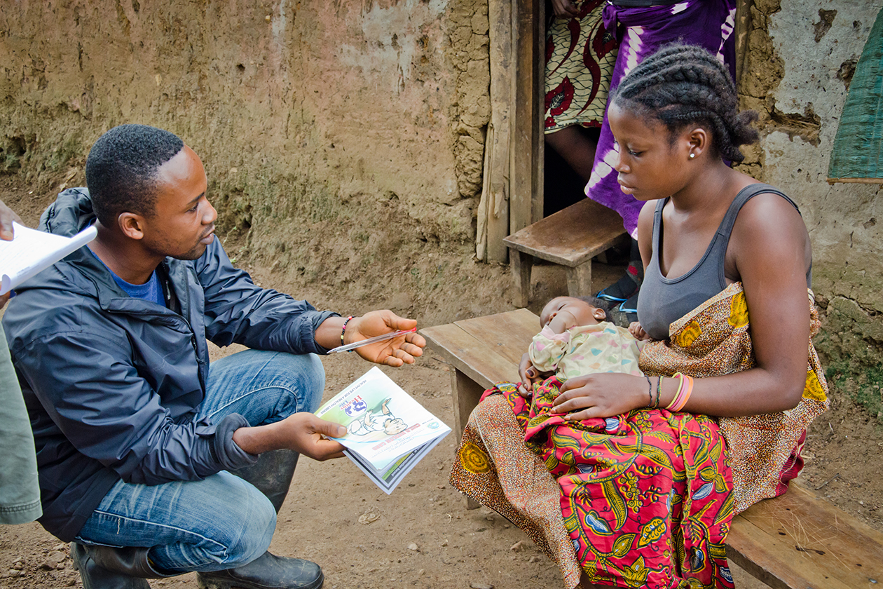 A community health worker speaks to a young mother in rural Rivercess County.