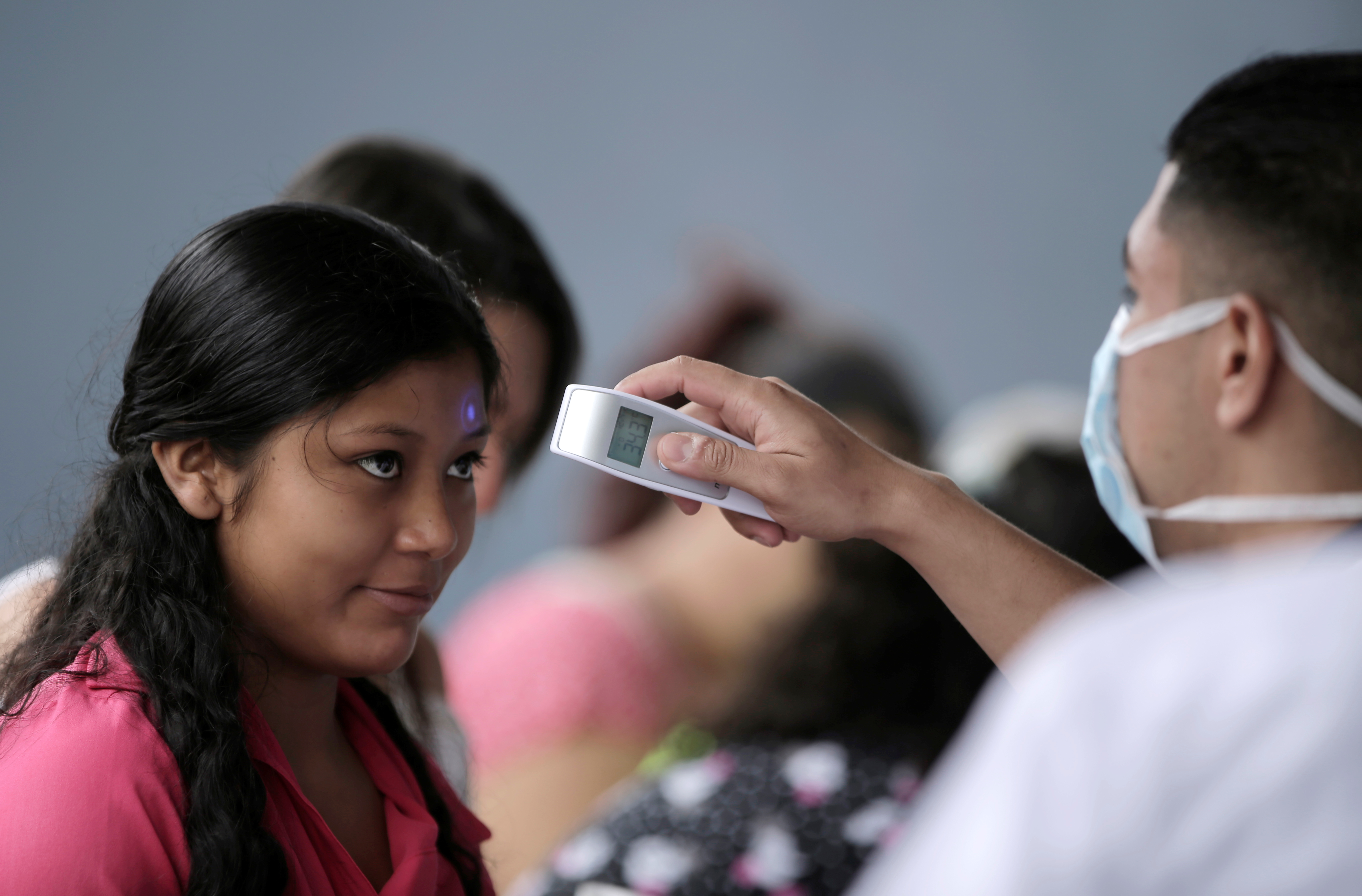 A public health worker records a woman’s temperature before she enters a health center, as part of preventive measure against COVID-19, in San José, Costa Rica, March 12, 2020. 