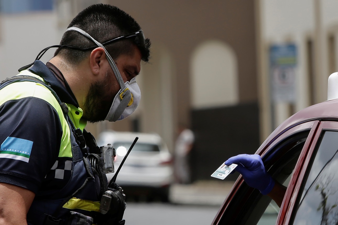 A police officer checks the identity card of a vehicle’s occupant following the imposition of restrictions by Costa Rica’s government to prevent the spread of COVID-19, in San José, Costa Rica, April 10, 2020. 