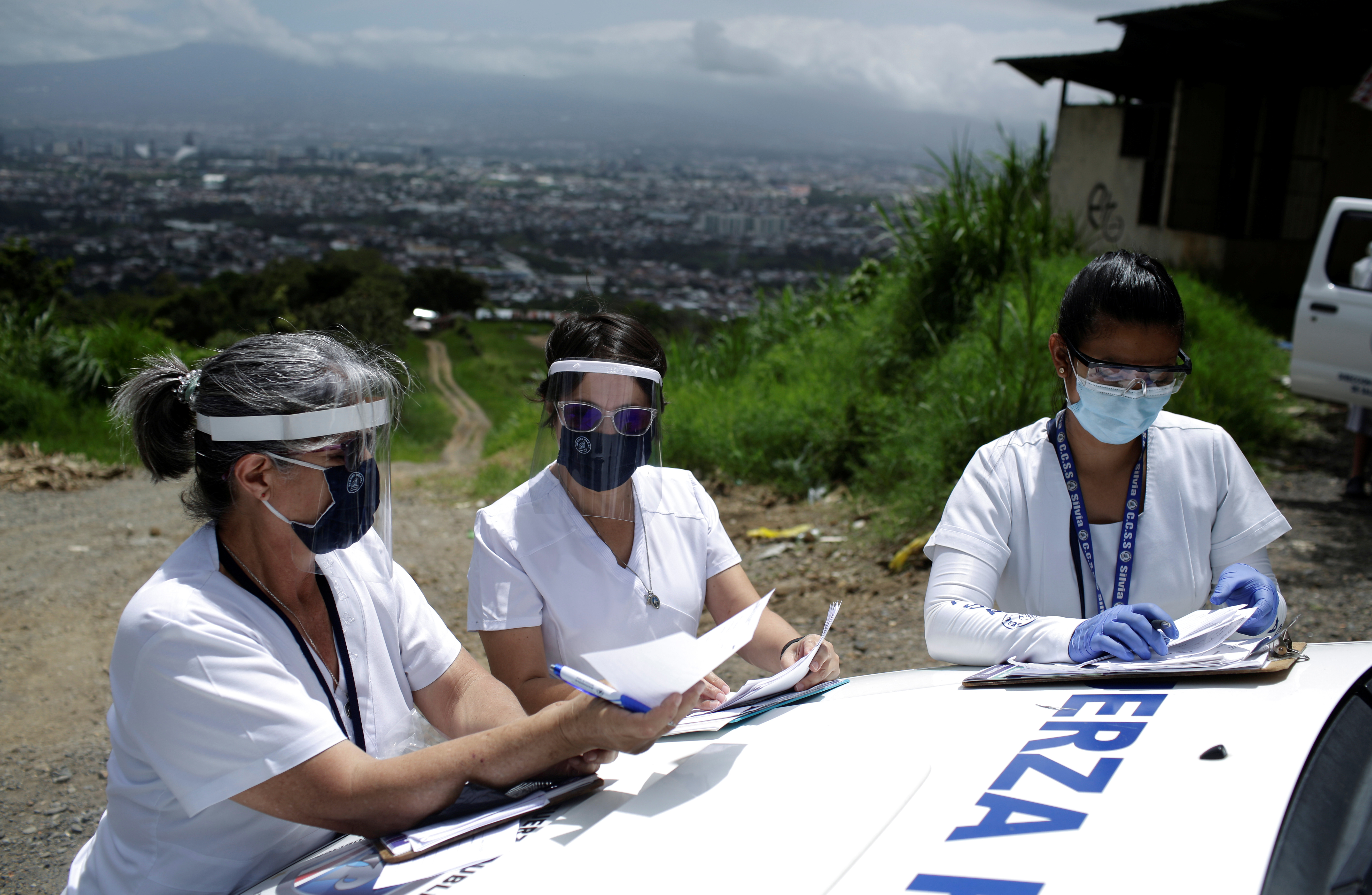 Health workers collect data from people who have been tested for COVID-19 in a densely populated, low-income area in San José, Costa Rica, July 7, 2020.