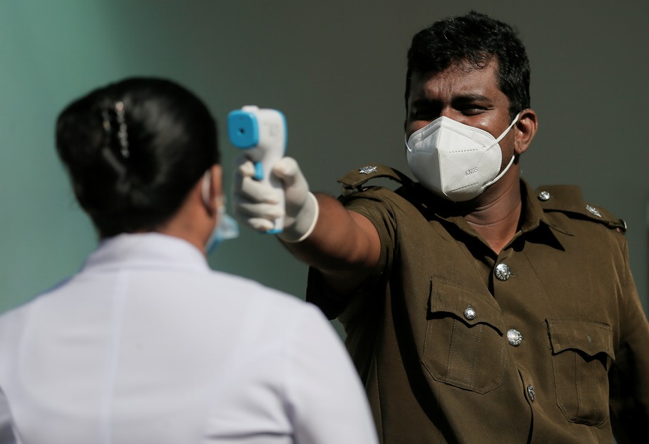 A health official uses a thermometer to take the temperature of a healthcare worker during a simulation exercise for the coronavirus disease (COVID-19) vaccination in the Piliyandala suburb, south of Colombo, Sri Lanka January 23, 2021.