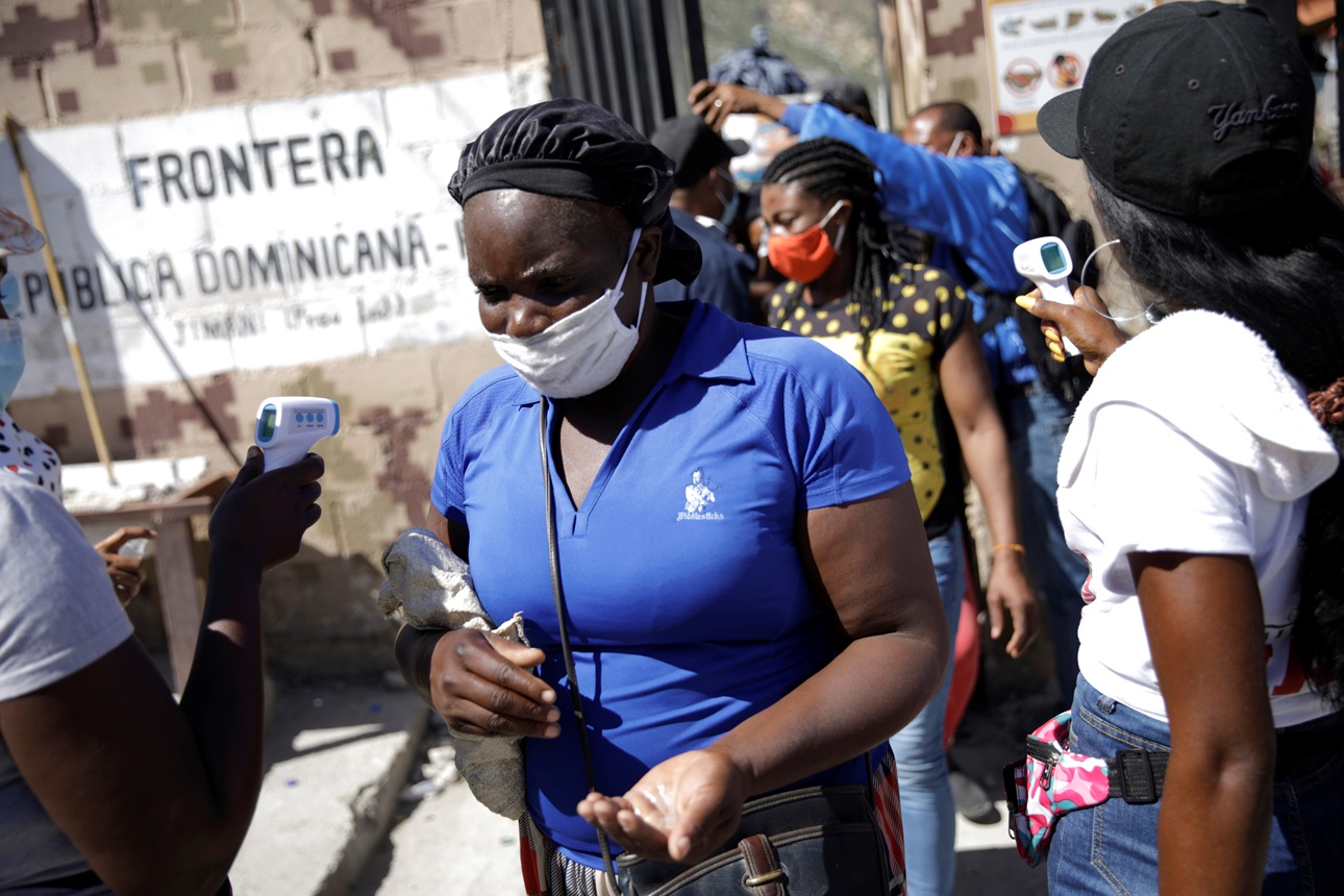 A woman coming from Haiti wears a face mask as she gets her temperature checked and receives sanitizer gel at the border between Malpasse, in Haiti, and Jimani, in Dominican Republic, as the border remained open for commercial purposes, Jimani, Dominican Republic, October 29, 2020.