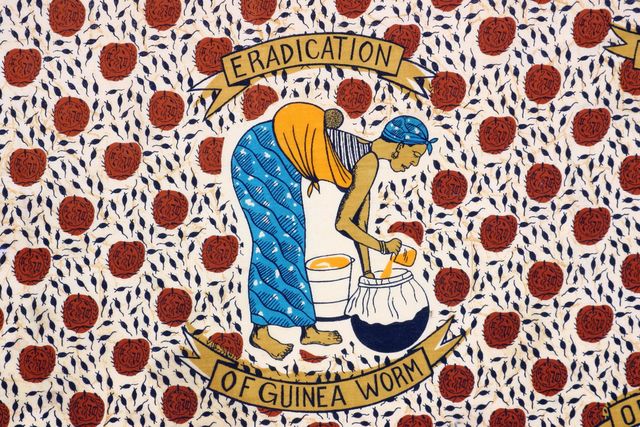 Detail of a cloth from Togo depicting a woman filtering water to prevent Guinea Worm.