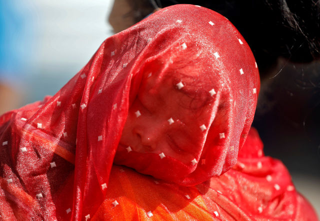 A migrant worker covers her child with a sari to protect them from the heat in Ahmedabad.