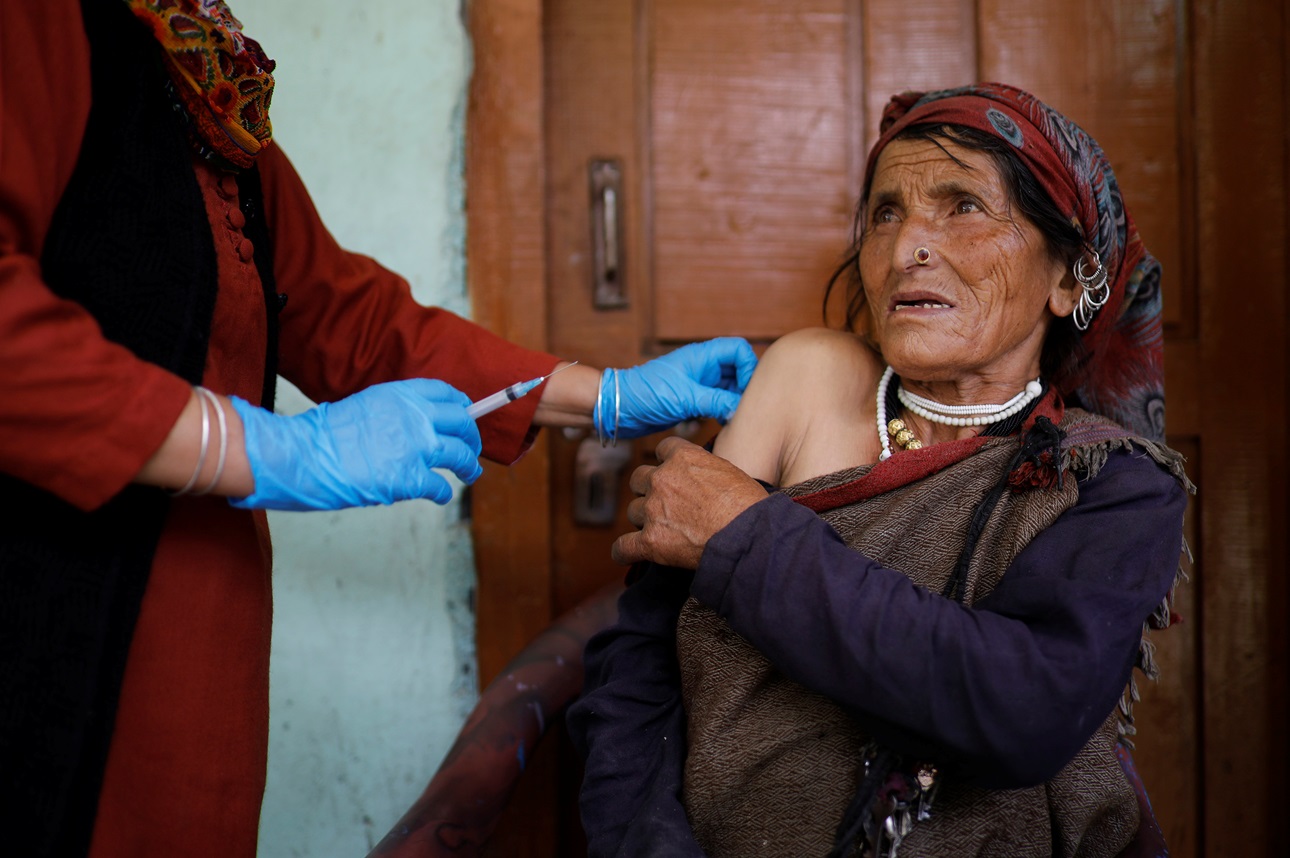 A community health worker gives a COVID vaccine to a villager in India.