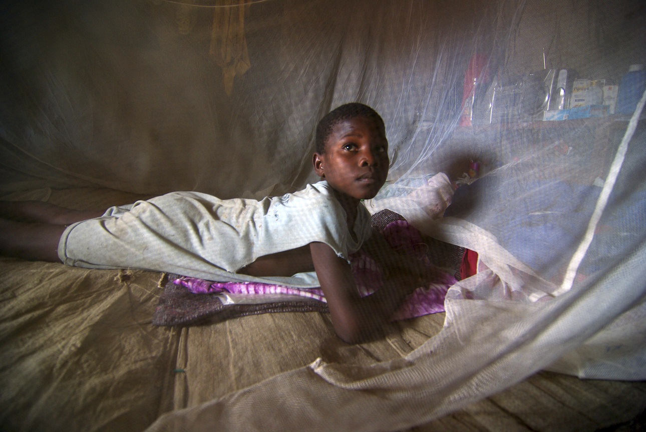 A girl inside a mosquito net to prevent malaria in Sierra Leone.