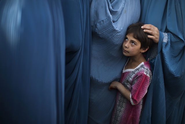An Afghan girl stands in line with her mother to receive food on the outskirts of Kabul.