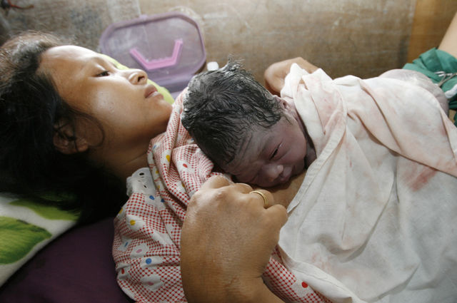A newly born baby boy rests on the chest of his mother.