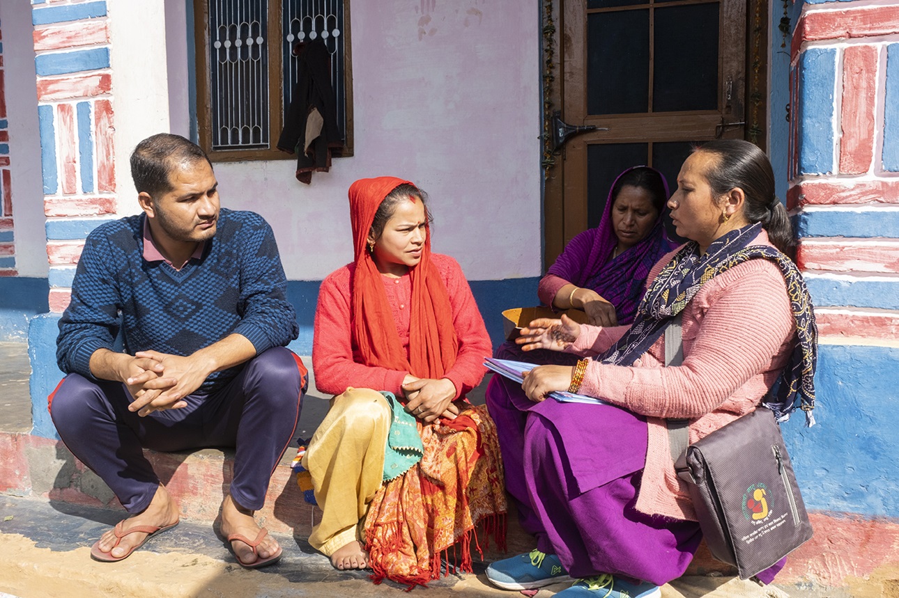 A community health worker in India (Anganwadi worker) consults with a pregnant woman and her family during a home antenatal care visit