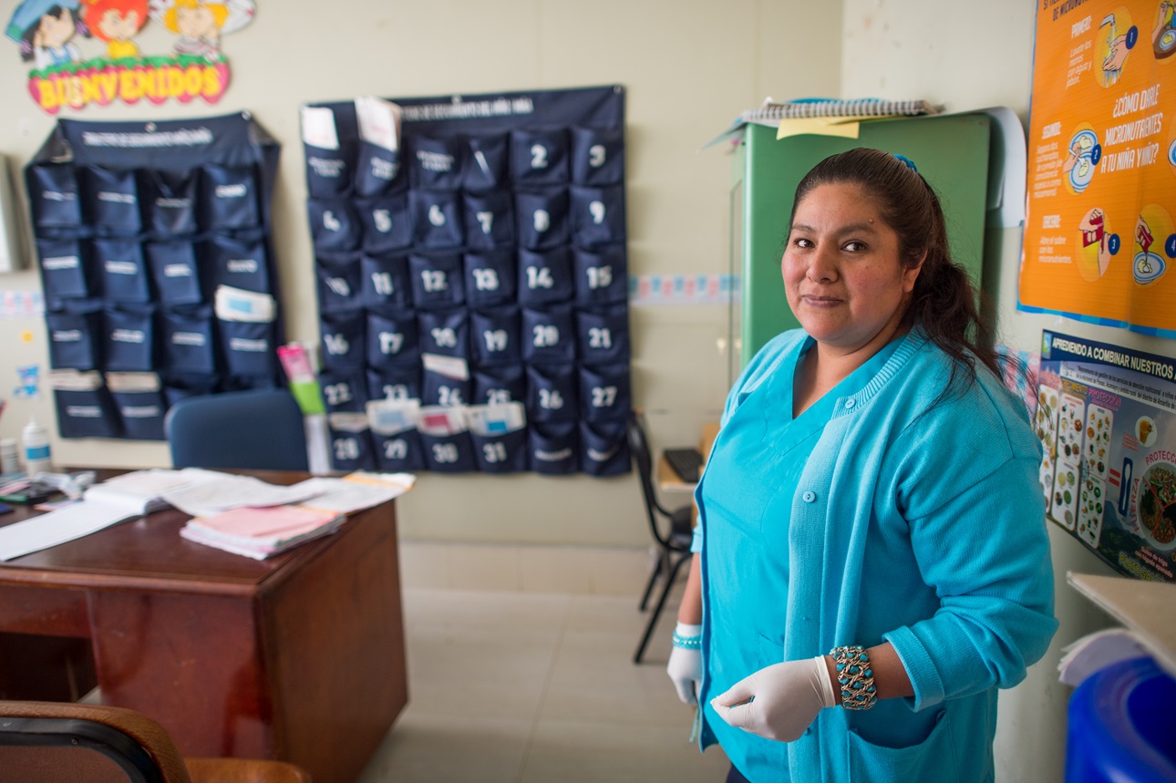 A nurse poses for a photo after recording the height and weight of a child at a health clinic in Acomayo, within the Chinchao district of Huanuco, Peru on August 28, 2017. Families residing here are the beneficiaries of JUNTOS, a cash transfer program conditional on adherence to various social programs.
