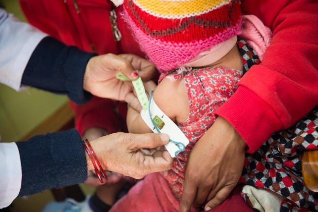 A nurse measures a child’s arm circumference in Nepal, where childhood wasting is still prevalent.