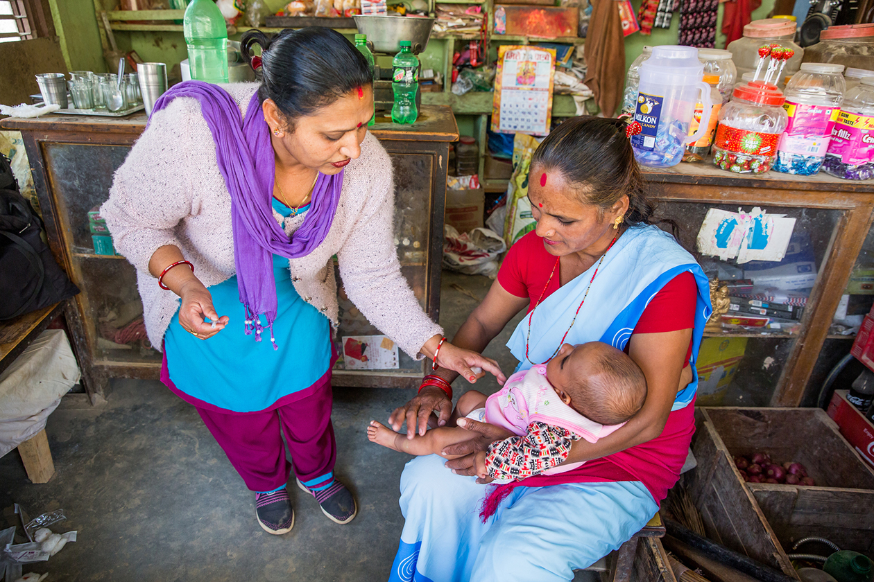 Community health workers immunize a three-month-old child at the Lekhnath Dai ko Pasal Outreach Clinic in Sudal, Bhaktapur, Nepal.