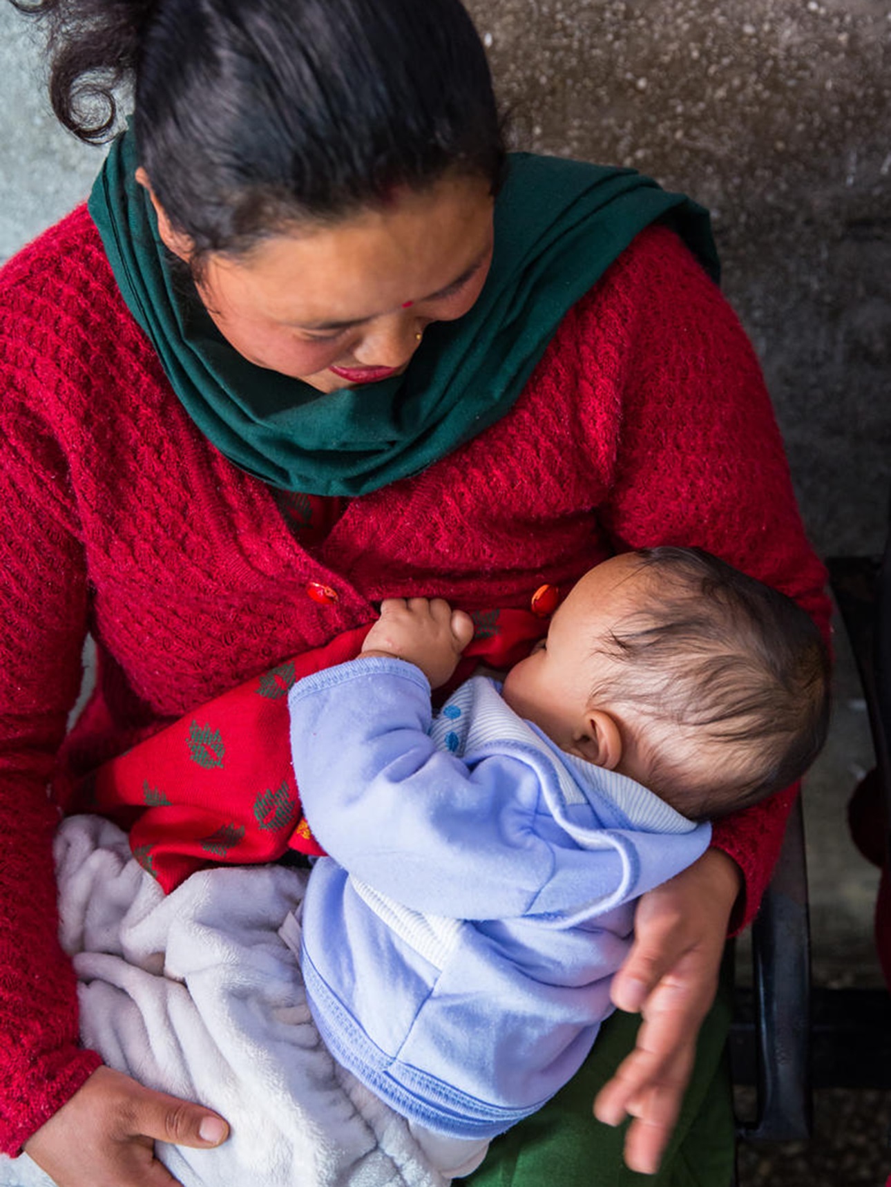 A mother breastfeeds her infant son after receiving a vaccination in Nepal. 