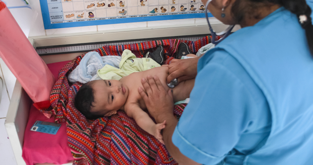 A health care worker in Peru checks the height, weight, and health of an infant.