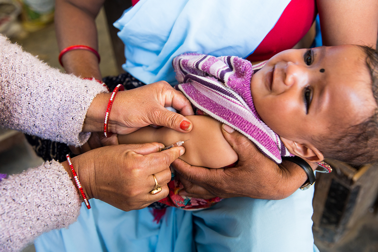 A child in Nepal receives a vaccination from a health worker.