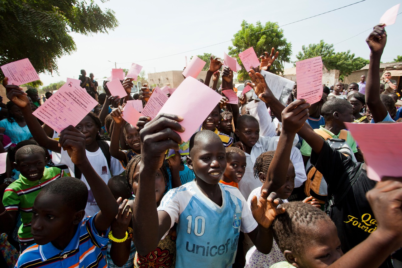 Children hold up their vaccination cards during a vaccination clinic campaign in Senegal